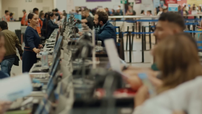 Der Reisende aus Iberias Kampagne „El dilema de Navidad“ spricht mit einer Mitarbeiterin am Check-in-Schalter